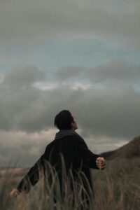 "A person standing with arms raised, surrounded by fog and mountains, symbolizing the search for hope and liberation amidst uncertainty.